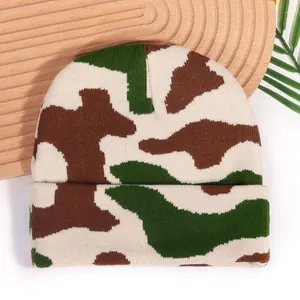 Y2K camouflage jacquard knit beanie with rolled cuff on a natural wooden tray