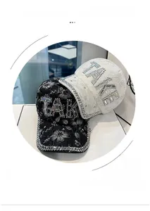 Detail showing the rhinestone encrusted TAKE lettering on lace floral baseball caps