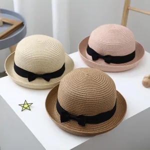 Detail view of woven straw hats in cream, pink, and brown with black bow ribbons