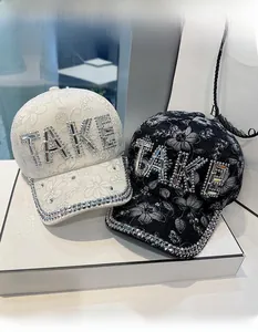 Close-up of floral lace baseball caps with sparkling rhinestone TAKE letter design