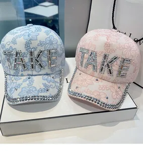 Detailed view of floral lace baseball caps with rhinestone TAKE lettering and crystal trim