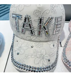 Macro shot of white lace baseball cap with sparkling crystal TAKE letters and rhinestone brim