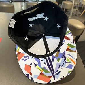 Détail de la casquette à bord plat montrant l'imprimé géométrique et l'étiquette 100% coton