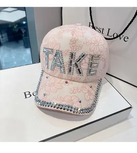 Macro detail of pink floral lace baseball cap with sparkling rhinestone TAKE lettering