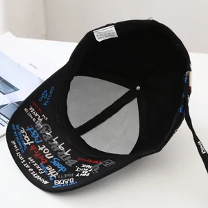 Detailed top view of a black cotton baseball cap with colorful graffiti and internal cotton label