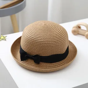 Detail of children's straw beach hat with dense weave and black ribbon bow decoration