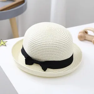 Detail of kids beige straw hat featuring a black ribbon bow and fine woven texture