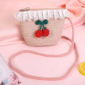Detail shot of a pink straw bag featuring delicate white lace trim and cherry decor