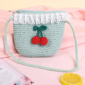 Detail of blue straw bag featuring white lace trim and knitted cherry ornaments