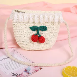 Detail of children's straw bag with lace trim and crochet cherry charms on pink fabric