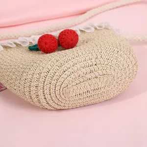 Kids straw crossbody bag with cute lace trim and red cherry charms on pink background