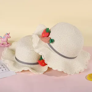 Detail of straw hats for kids featuring ruffled edges with strawberry and carrot charms