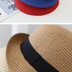 Close-up of high-density woven straw hats with decorative black ribbons in various colors