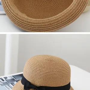 Detail of hand-woven straw sun hat texture featuring a black ribbon bow and wide brim