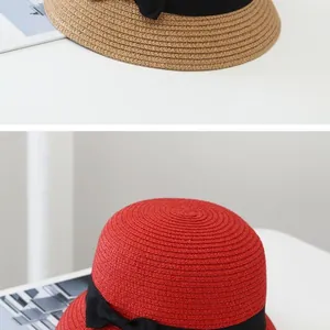 Detail view of woven straw hats in khaki and red with black ribbon bow decoration