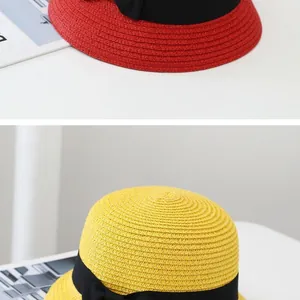 Detail of red and yellow woven straw hats with black grosgrain ribbon and bow accents