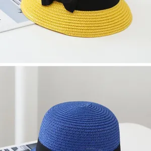 Detail of hand-woven straw hats in yellow and blue with elegant black ribbon bows