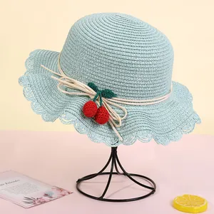 Pale green straw sun hat with ruffled brim and cherry accents for summer beach vacation