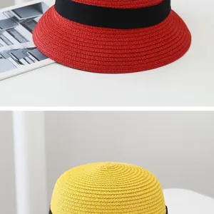 Detail of red and yellow woven straw hats with black grosgrain ribbon and spiral texture