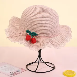 Detail of pink straw sun hat with ruffled brim and handmade crochet cherry decorations