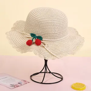 Detailed view of woven straw hat featuring ruffled edges and handmade crochet cherries