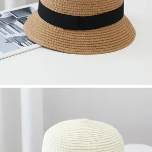 Detail of fine straw weave texture on sun hats in beige and khaki with black ribbon