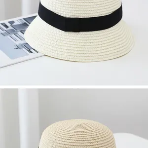 Detail of cream woven straw hat with black ribbon, showcasing fine texture and brim curve