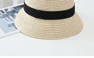 Close-up of straw sun hat featuring neat weave texture and decorative black ribbon