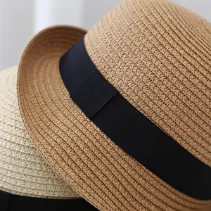 Women's woven straw sun hat with black ribbon detail in light brown and cream colors