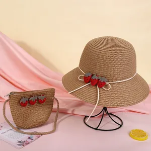 Details von Strohhut und passender Tasche mit Erdbeer-Patches und weißer Schleifendekoration