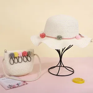 Detalle de conjunto de sombrero y bolso de paja para niños con pompones de colores