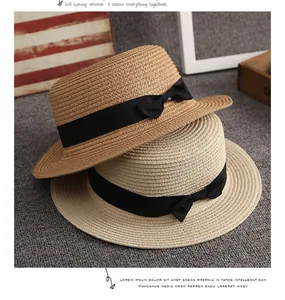 Dettaglio di cappelli di paglia in kaki e beige con eleganti fiocchi di nastro nero