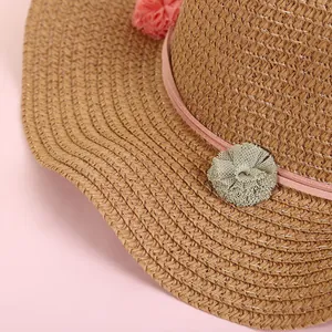 Sombrero de paja infantil con pompones rosas y flores de malla decorativas