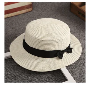 Dettaglio di un cappello di paglia crema con nastro nero e fiocco dal design retrò