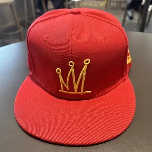 Détail d'une casquette hip-hop rouge à bord plat avec broderie couronne jaune et coton