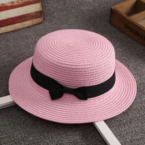 Pink woven boater hat for women featuring a stylish wide black ribbon bow decoration
