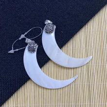 Détail macro de pendentifs lune en nacre avec bélière argentée incrustée de pierres