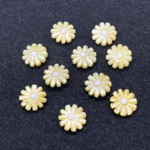 Detailed view of yellow flower beads made from natural shell scattered on black texture