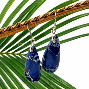 Blue teardrop natural stone earring hanging on a branch with tropical leaves