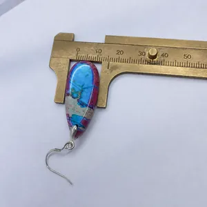 Macro detail of tear-drop natural stone earrings measured with a vintage brass caliper