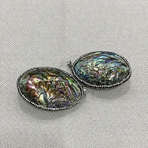 Detailansicht ovaler Abalone-Anhänger mit Strassrand und Metallösen für Halsketten