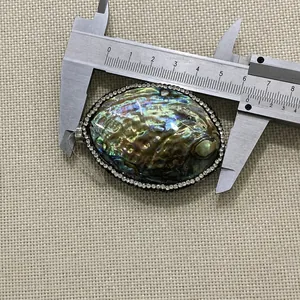Makroansicht des ovalen Abalone-Anhängers mit Strasssteinen bei 5,5 cm Länge gemessen