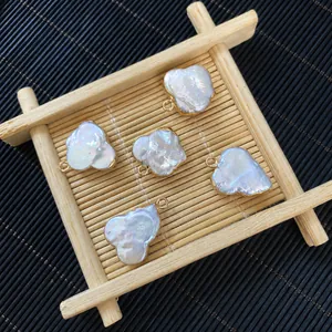 Baroque style freshwater pearl charms with gold plating edges on a textured tray