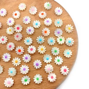 Detailed view of colorful shell daisy beads for DIY jewelry making in a wooden tray