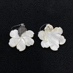 Détails de pendentifs fleur en nacre avec pierres sur fond de tissu noir