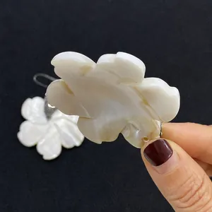 Vue détaillée du pendentif fleur en nacre avec reflets irisés et bords sculptés