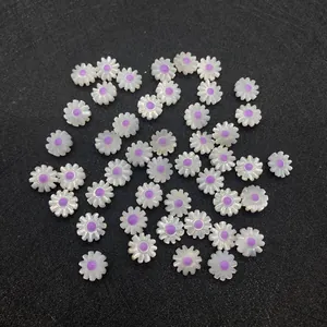 Macro detail of white shell daisy beads with purple centers on textured black background