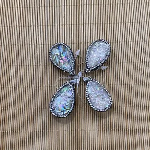 Détail de quatre pendentifs en forme de goutte en nacre d'abalone et cristal avec strass