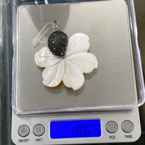Vue détaillée du poids de 18,65g du pendentif fleur en nacre avec cristaux noirs