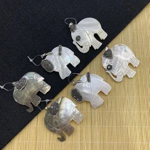 Elephant shell pendant with glittering crystals and metallic luster on textured background